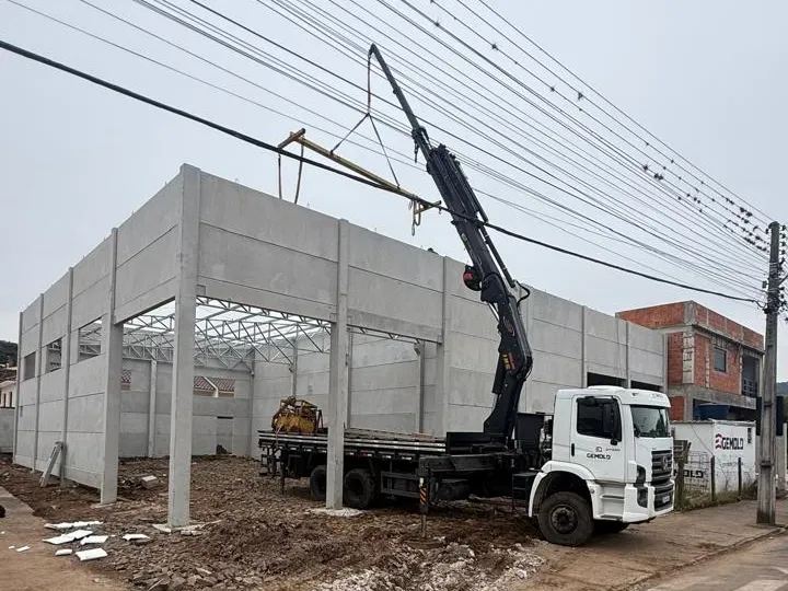Paredes de placas pré-moldadas encaixadas entre os pilares, com o munck da Gemold na obra
